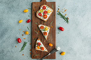 Tomato Toasts with Herbed Farmer's Cheese on a wooden board